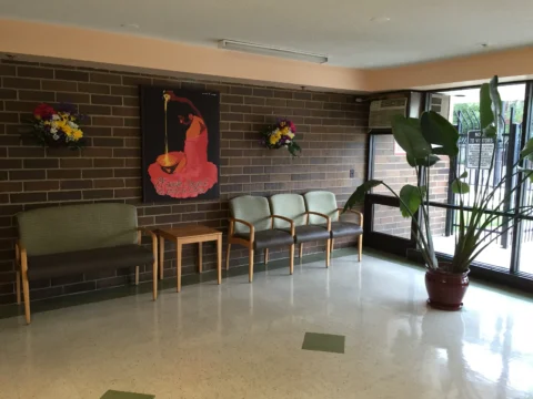 The entrance to the Armitage Commons Apartments, with chairs lined against a brick wall next to a bright floor-to-ceiling window.