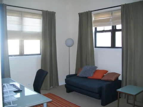 A spare bedroom or den of the Boulevard Court apartments, showing several windows, a futon, and desk with a computer chair.