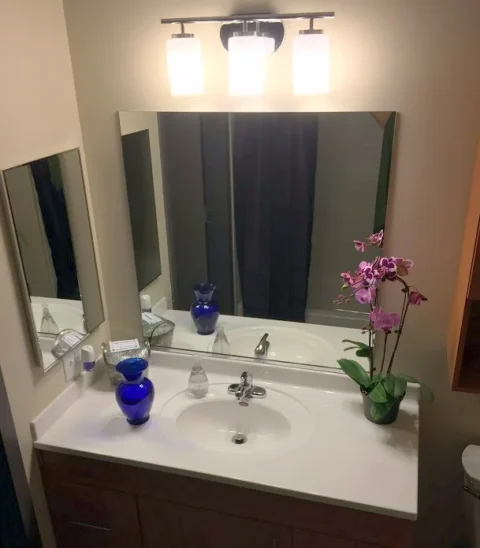 A bathroom sink, with tall mirrors and a wide white counter.