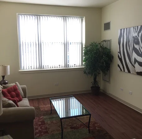 The living room has a glass table with couch, a large mounted painting, and a single large window.