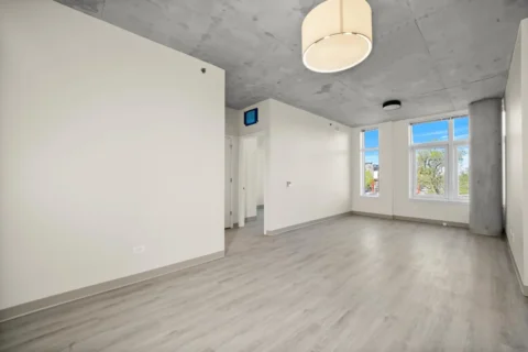 The living room has wood floors, large windows, and a large cement structural pillar in the corner.