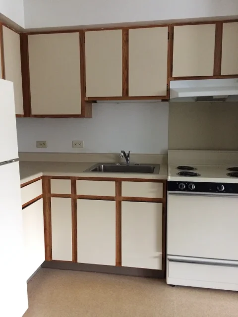 A kitchen with overhead and under counter cabinets, a four-burner stove, sink, and fridge.